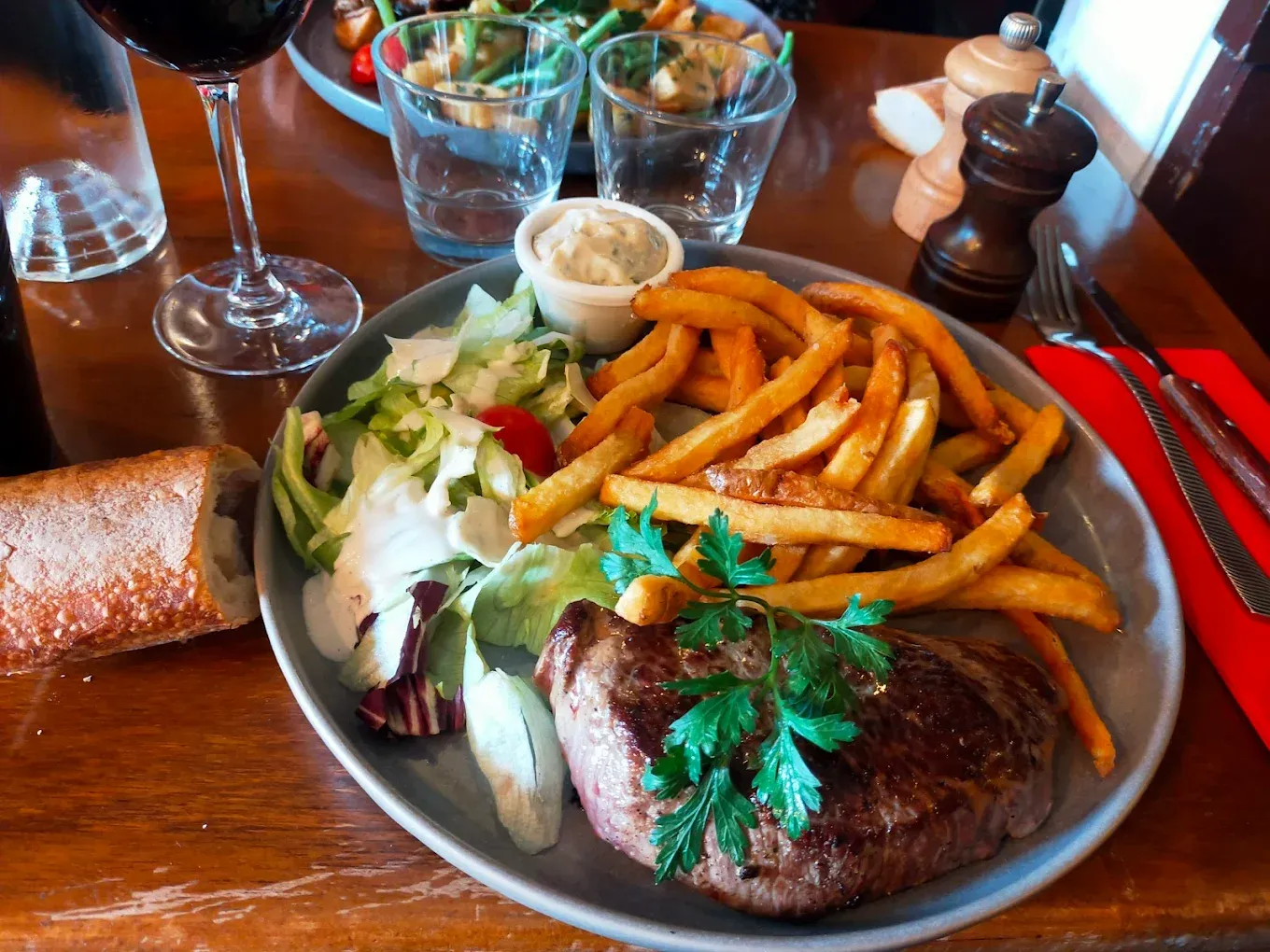 Piece du boucher grillee, frites maison, salade et verre de vin rouge