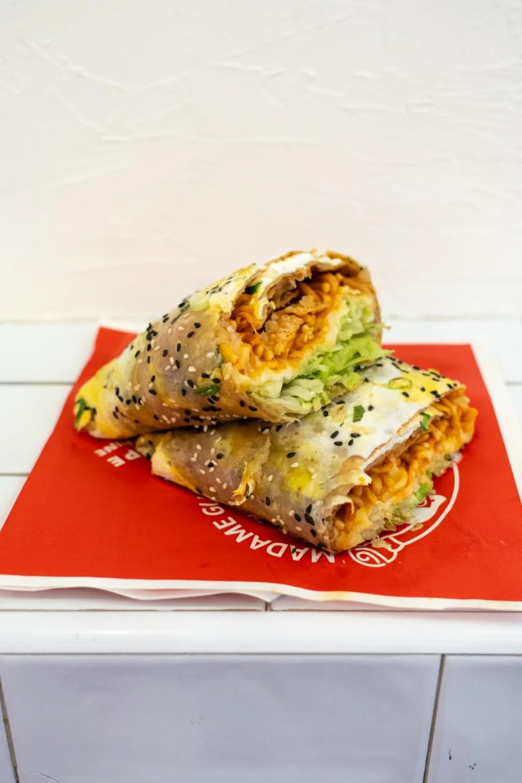 Jianbing aux nouilles pimentées et mozzarella, empilé sur le papier rouge de la maison