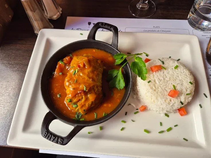 Un chou farci en cocotte de fonte avec du riz, servi sur le set de table du Pavé des Lombards