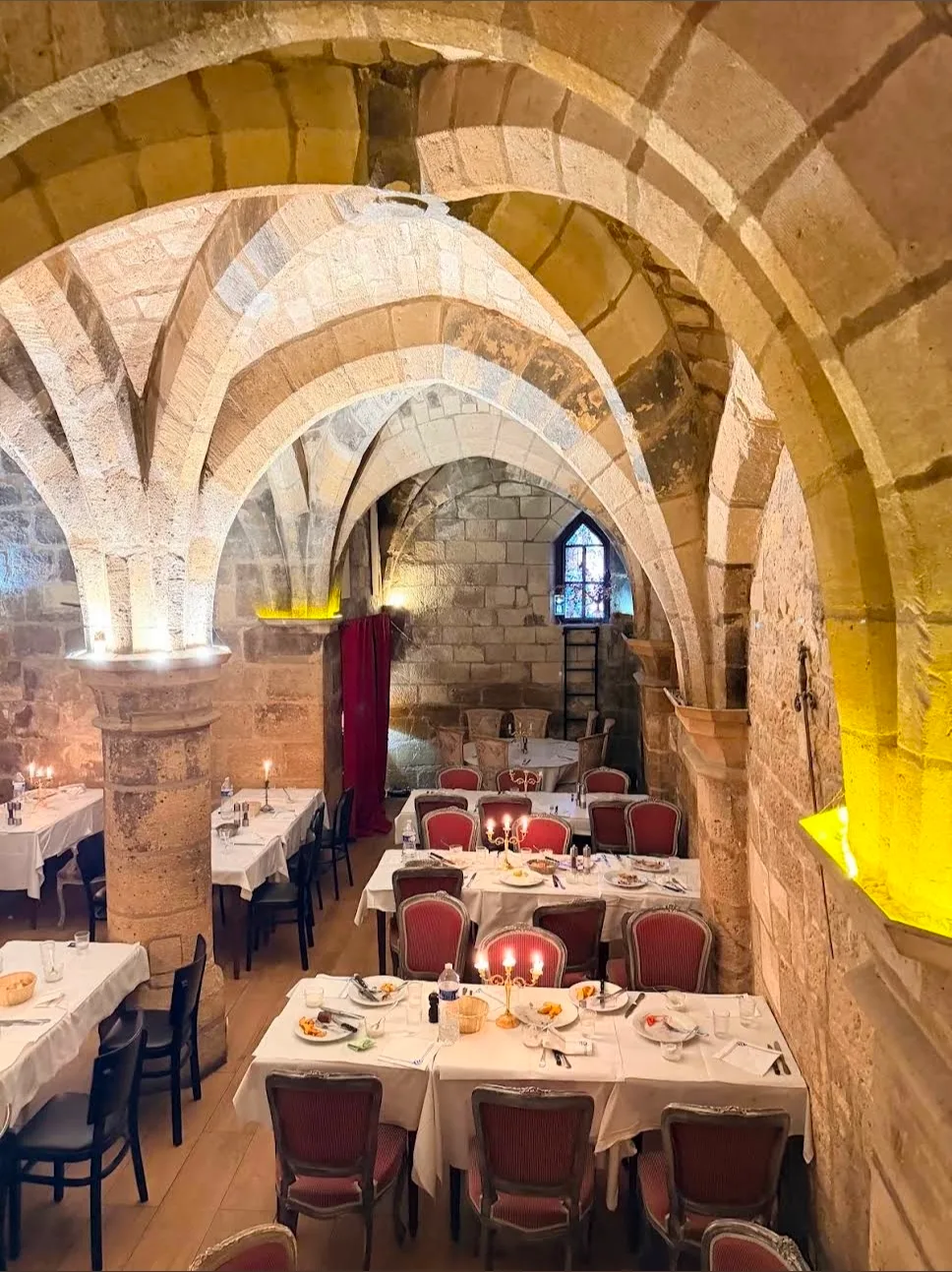 L'enfilade de voûtes, les tables dressées et les chandeliers allumés