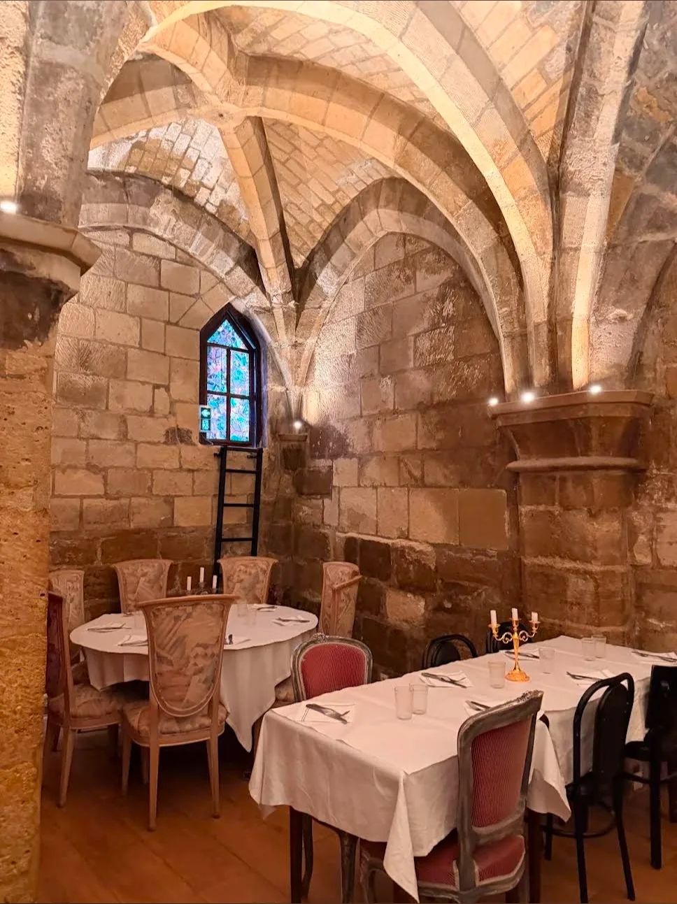 La salle voûtée de l'ancienne chapelle, son vitrail et ses tables dressées