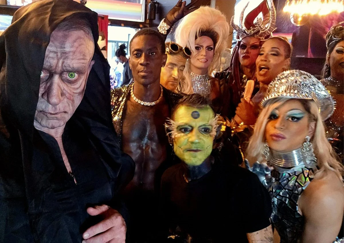 La troupe costumée dans la salle, drapeau arc-en-ciel au plafond