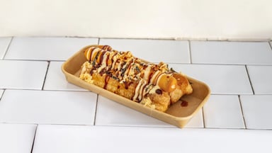 Chinese hotdog in you tiao, drizzled with sauces and fried onions